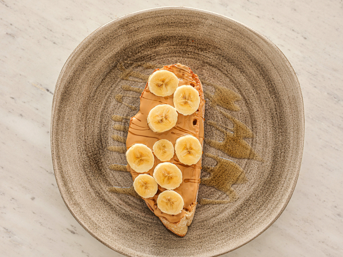 Banana-topped toast on a ceramic plate in natural light