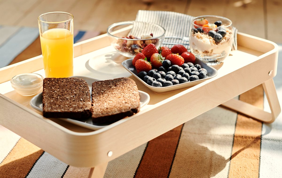 Breakfast tray with wholemeal toast, berries, yoghurt and orange juice in natural light