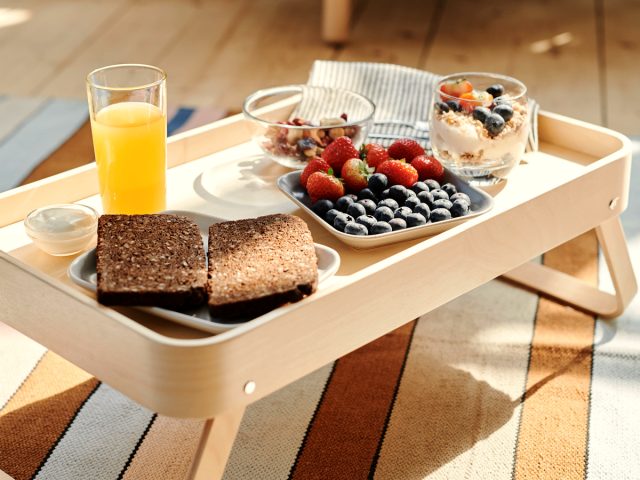 Breakfast tray with wholemeal toast, berries, yoghurt and orange juice in natural light